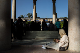 زنی در حال خواندن دیوان حافظ در گوشه ای از عمارت حافظیه