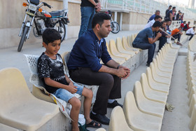 استفاده تماشاچیان از روزنامه برای نشستن بر روی صندلی های خاکی «خلیج فارس» بندرعباس
