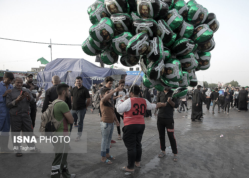 فروش بادکنک هایی با نقش تصاویری‌ منتصب به امام حسین(ع) در حاشیه‌ی مسیر راهپیمایی بزرگ اربعین.