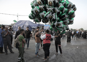 فروش بادکنک هایی با نقش تصاویری‌ منتصب به امام حسین(ع) در حاشیه‌ی مسیر راهپیمایی بزرگ اربعین.