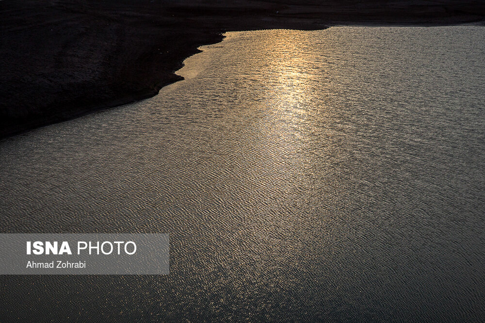 انعکاس نور خورشید در غروب که بر روی باقیمانده آب پشت سد چشم نوازی می کند.