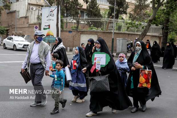 خانواده ای در مراسم راهپیمایی روز جهانی قدس در میدان فلسطین جهت اقامه نماز سمت دانشگاه تهران راهی می شوند