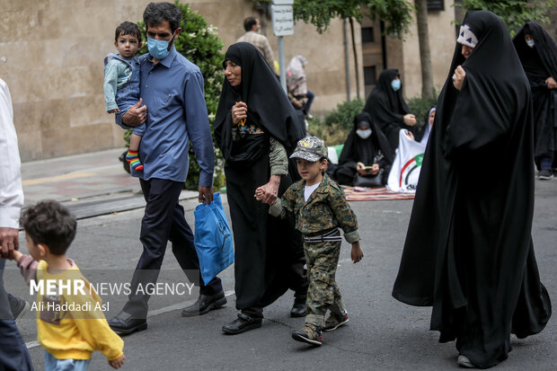 کودکی با لباسی نظامی و به همراه خانواده در راهپیمایی روز جهانی قدس در میدان فلسطین حضور دارد