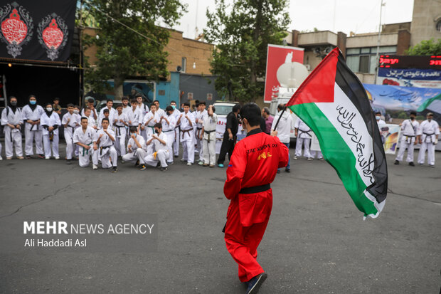 جوان رزمی کاری با برافراشتن پرچم فلسطین در راهپیمایی روز جهانی قدس در تهران حضور دارد